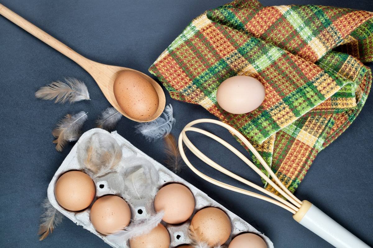 Egg boiler with silicone poaching cups inserted, filled with raw eggs, placed over water reservoir—ready to steam-poach.